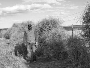 Michael Castle standing next to a tower of tumbleweeds hiding his fence.